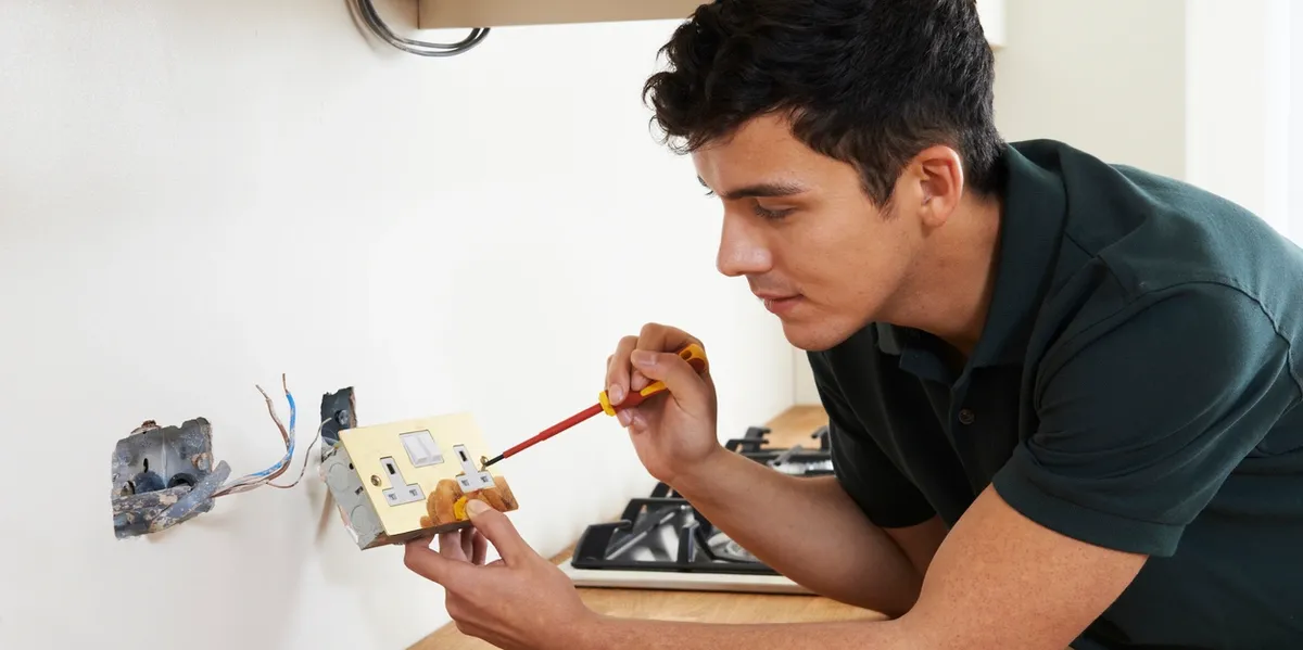 A man painting a small wooden model with a fine brush.