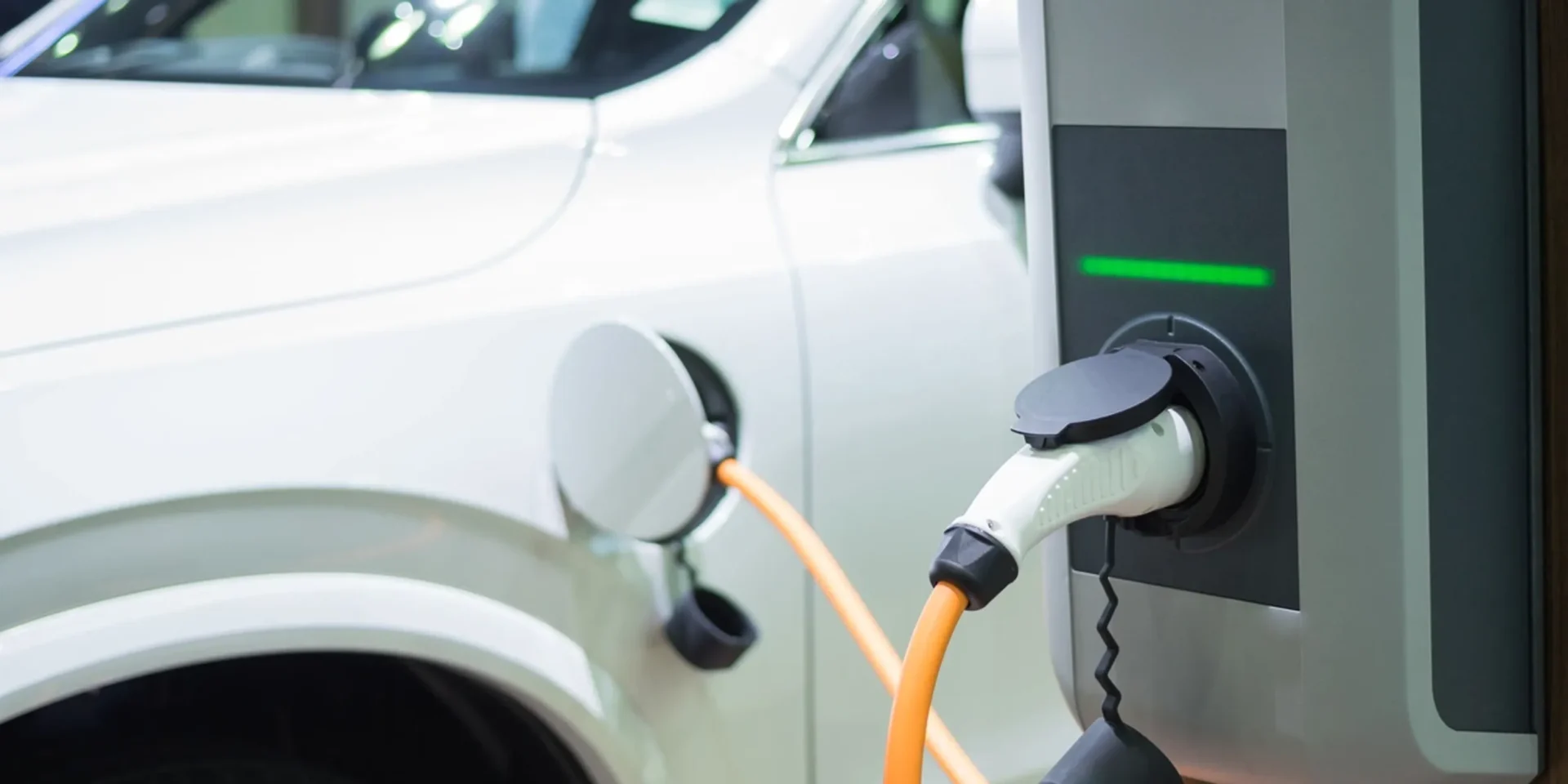 Electric car charging at a station with a visible charging cable.